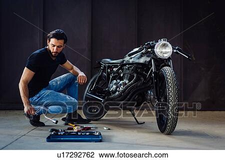 Young male motorcyclist doing maintenance on vintage motorcycle in garage View Large Photo Image Stock Image - Young male motorcyclist doing maintenance on vintage motorcycle in garage. Fotosearch