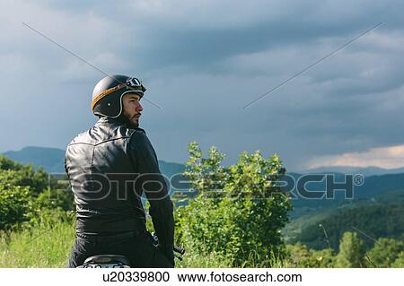 Young male motorcyclist on motorcycle looking over his shoulder, Florence, Tuscany, Italy View Large Photo Image Stock Image - Young male motorcyclist on motorcycle looking over his shoulder, Florence, Tuscany, Italy. Fotosearch