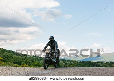Young male motorcyclist on vintage motorcycle on rural road, Florence, Tuscany, Italy View Large Photo Image Picture - Young male motorcyclist on vintage motorcycle on rural road, Florence, Tuscany, Italy. Fotosearch