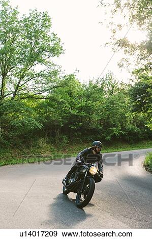Young male motorcyclist on vintage motorcycle on rural road bend, Florence, Tuscany, Italy View Large Photo Image Stock Photo - Young male motorcyclist on vintage motorcycle on rural road bend, Florence, Tuscany, Italy. Fotosearch