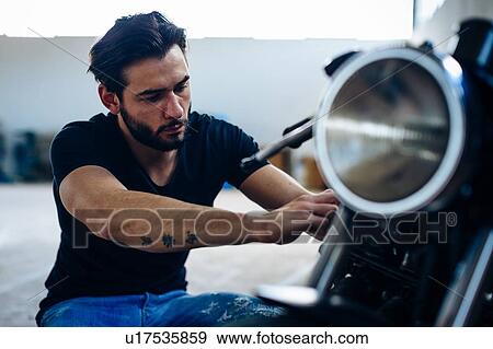 Young male motorcyclist repairing vintage motorcycle outdoors View Large Photo Image Stock Photo - Young male motorcyclist repairing vintage motorcycle outdoors. Fotosearch