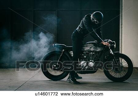 Young male motorcyclist revving vintage motorcycle in garage View Large Photo Image Stock Image - Young male motorcyclist revving vintage motorcycle in garage. Fotosearch