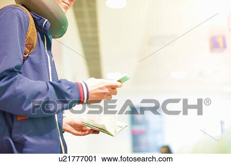 Young man at airport, using smartphone, holding passport, mid section, low angle view View Large Photo Image Stock Image - Young man at airport, using smartphone, holding passport, mid section, low angle view. Fotosearch
