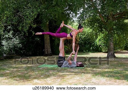 Young man practicing yoga in garden, lying on back balancing woman on feet View Large Photo Image Stock Image - Young man practicing yoga in garden, lying on back balancing woman on feet. Fotosearch