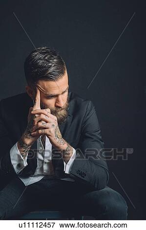Young man wearing suit, sitting with worried expression, tattoos on hands View Large Photo Image Stock Photo - Young man wearing suit, sitting with worried expression, tattoos on hands. Fotosearch