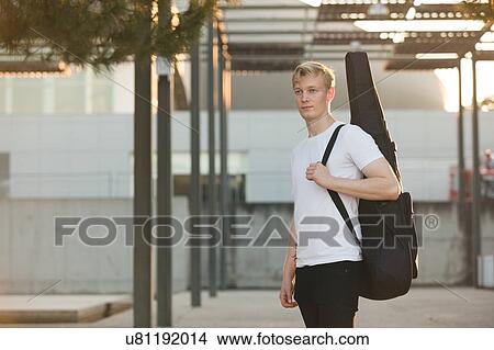 Young musician carrying guitar in case View Large Photo Image Picture - Young musician carrying guitar in case. Fotosearch