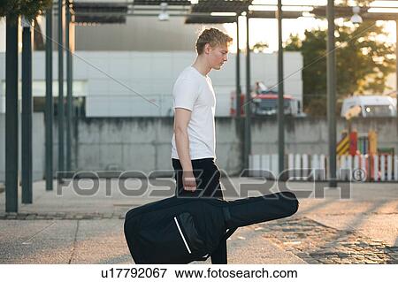 Stock Photo - Young musician carrying guitar in case. Fotosearch
