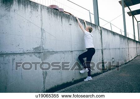 Stock Photography - Young musician climbing wall. Fotosearch