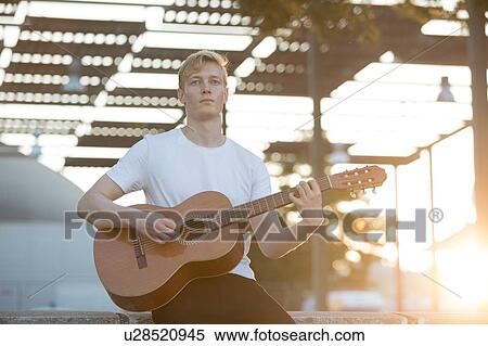 Stock Photography - Young musician playing guitar in park. Fotosearch
