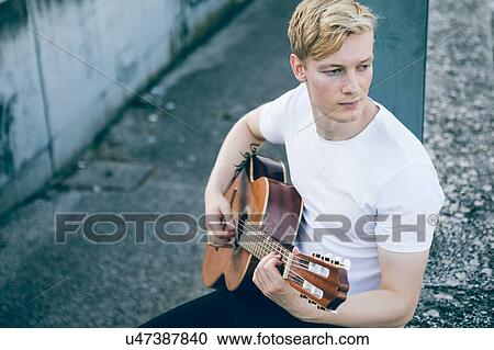 Stock Image - Young musician playing guitar. Fotosearch