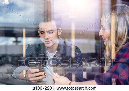 Young students looking at smartphones in cafe window seat, view through window View Large Photo Image Stock Image - Young students looking at smartphones in cafe window seat, view through window. Fotosearch