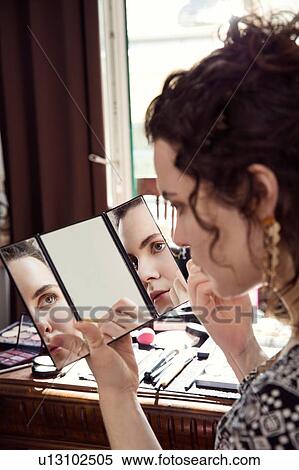 Young woman applying make up in bedroom View Large Photo Image Stock Photography - Young woman applying make up in bedroom. Fotosearch