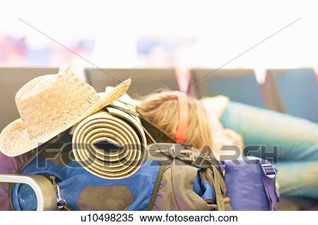 Young woman at airport, sleeping on seating in departure lounge, resting head on backpack, top section View Large Photo Image Stock Photography - Young woman at airport, sleeping on seating in departure lounge, resting head on backpack, top section. Fotosearch