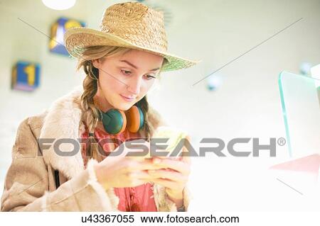Young woman at airport, using smartphone, headphones around neck View Large Photo Image Stock Photography - Young woman at airport, using smartphone, headphones around neck. Fotosearch