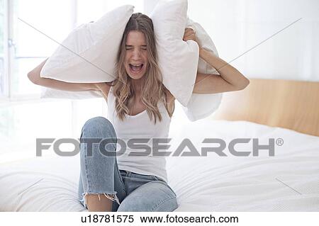 Young woman holding pillow over her ears and screaming View Large Photo Image Stock Photography - Young woman holding pillow over her ears and screaming. Fotosearch