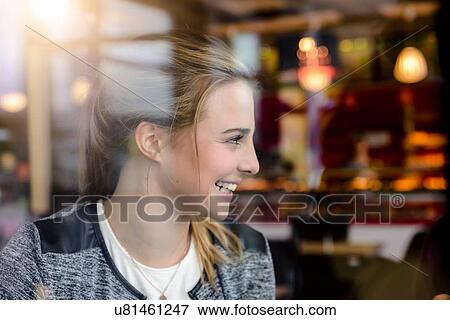 Stock Photo - Young woman in cafe window seat, view through window. Fotosearch