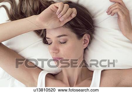 Young woman lying in bed with closed eyes View Large Photo Image Stock Image - Young woman lying in bed with closed eyes. Fotosearch