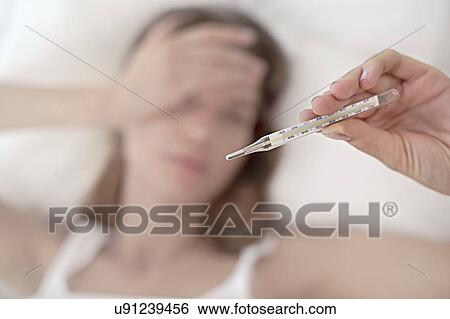 Stock Photograph - Young woman taking her temperature. Fotosearch