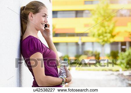 Stock Photo - Young woman talking on smartphone in park. Fotosearch