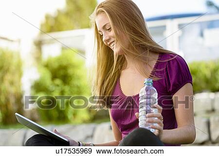 Young woman using digital tablet in park View Large Photo Image Stock Photo - Young woman using digital tablet in park. Fotosearch