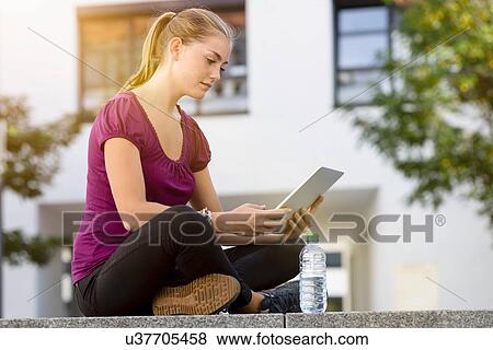 Young woman using digital tablet in park View Large Photo Image Stock Photo - Young woman using digital tablet in park. Fotosearch