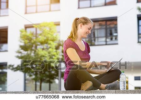 Stock Photo - Young woman using digital tablet in park. Fotosearch