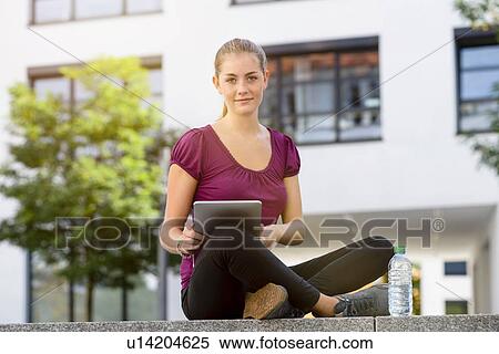 Young woman using digital tablet in park View Large Photo Image Stock Photography - Young woman using digital tablet in park. Fotosearch