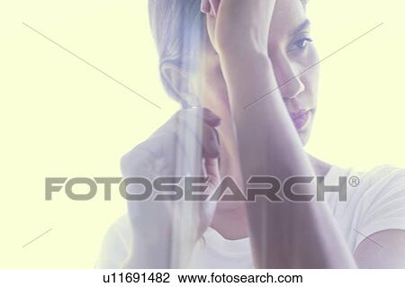 Stock Image - Young woman with eyes closed and head on hands. Fotosearch