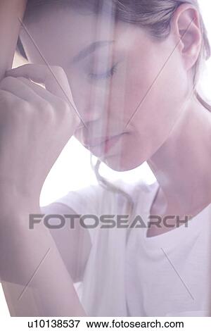 Stock Photo - Young woman with eyes closed and head on hands. Fotosearch
