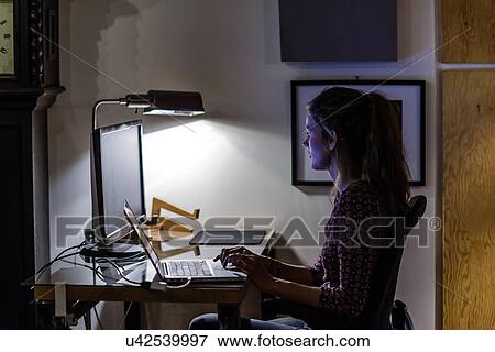 Young woman working late in office View Large Photo Image Stock Photo - Young woman working late in office. Fotosearch