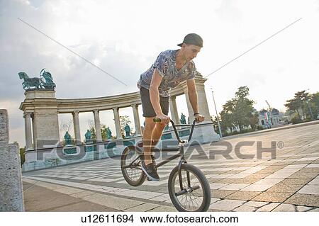 Picture - BMX cyclist doing nose wheelie, Heroes Square (Hosk Tere), Budapest, Hungary. Fotosearch