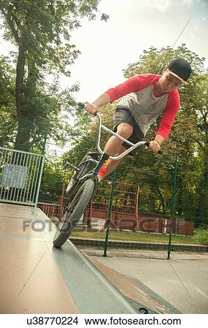 Picture - BMX cyclist doing nose wheelie on ramp. Fotosearch