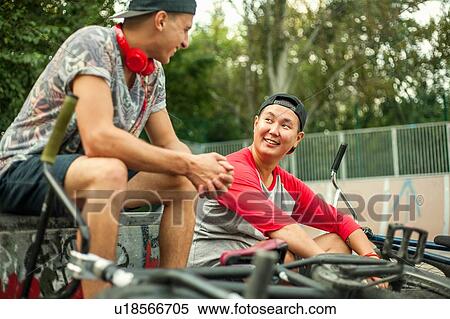 Stock Photography - BMX cyclists resting beside ramp. Fotosearch
