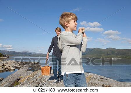 Stock Image - Boy and father carrying basket over inlet rock, Aure, More og Romsdal, Norway. Fotosearch