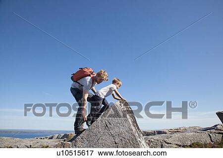 Boy and father climbing rock formation over inlet, Aure, More og Romsdal, Norway View Large Photo Image Stock Photo - Boy and father climbing rock formation over inlet, Aure, More og Romsdal, Norway. Fotosearch