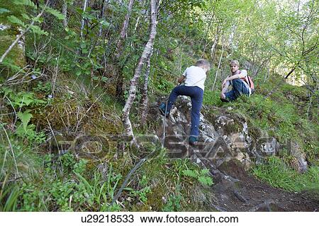 Stock Image - Boy and father climbing up mossy woodland, Aure, More og Romsdal, Norway. Fotosearch