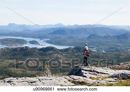 Stock Image - Boy and father looking out at inlet landscape from rock formation, Aure, More og Romsdal, Norway. Fotosearch