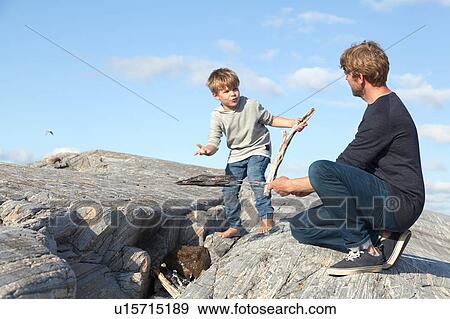 Stock Photo - Boy and father preparing campfire on inlet rock, Aure, More og Romsdal, Norway. Fotosearch
