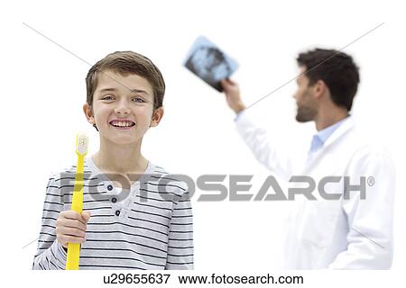 Boy holding over sized toothbrush in dental surgery, with doctor holding dental x-ray. View Large Photo Image Stock Photo - Boy holding over sized toothbrush in dental surgery, with doctor holding dental x-ray.. Fotosearch