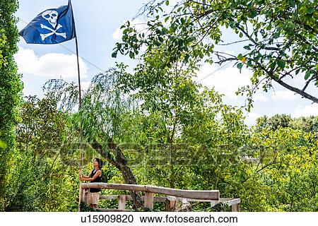 Stock Image - Boy on tree house with pirate flag. Fotosearch