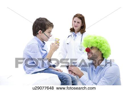Stock Photo - Boy using nebuliser with doctor dressed as clown.. Fotosearch