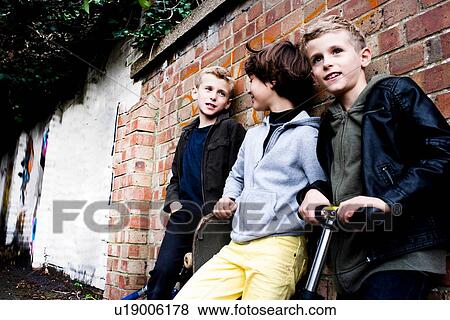 Stock Photo - Boys leaning against brickwall. Fotosearch