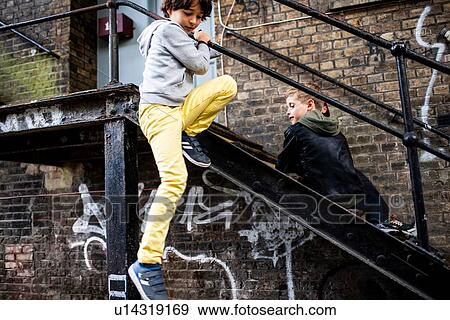 Stock Photo - Boys playing on metal staircase. Fotosearch