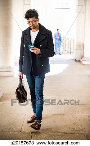 Stock Image - Businessman using smartphone in city. Fotosearch