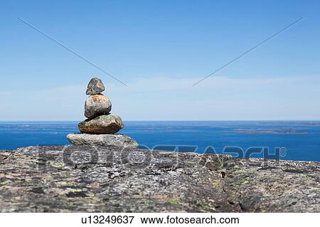 Stock Photo - Cairn on top of rock formation with inlet and blue sky, Aure, More og Romsdal, Norway. Fotosearch