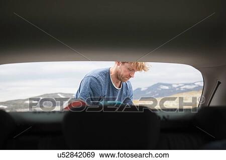Car hood view of mature man unpacking car, Oppland, Nord-Trondelag, Norway View Large Photo Image Stock Photo - Car hood view of mature man unpacking car, Oppland, Nord-Trondelag, Norway. Fotosearch
