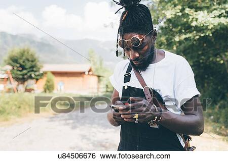 Cool young man on rural dirt track looking at smartphone, Primaluna, Trentino-Alto Adige, Italy View Large Photo Image Stock Photograph - Cool young man on rural dirt track looking at smartphone, Primaluna, Trentino-Alto Adige, Italy. Fotosearch