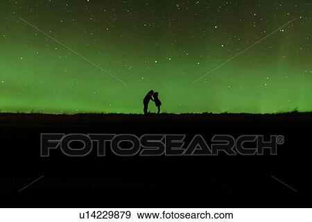 Stock Photo - Couple kissing in front of northern lights, Iceland. Fotosearch