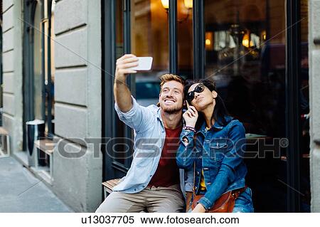 Stock Photography - Couple taking selfie by shop window, Milan, Italy. Fotosearch