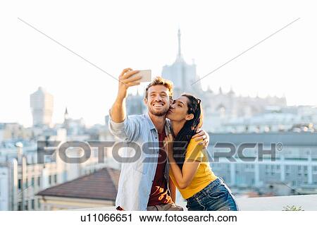 Couple taking selfie on edge of rooftop terrace, Milan, Italy View Large Photo Image Stock Image - Couple taking selfie on edge of rooftop terrace, Milan, Italy. Fotosearch